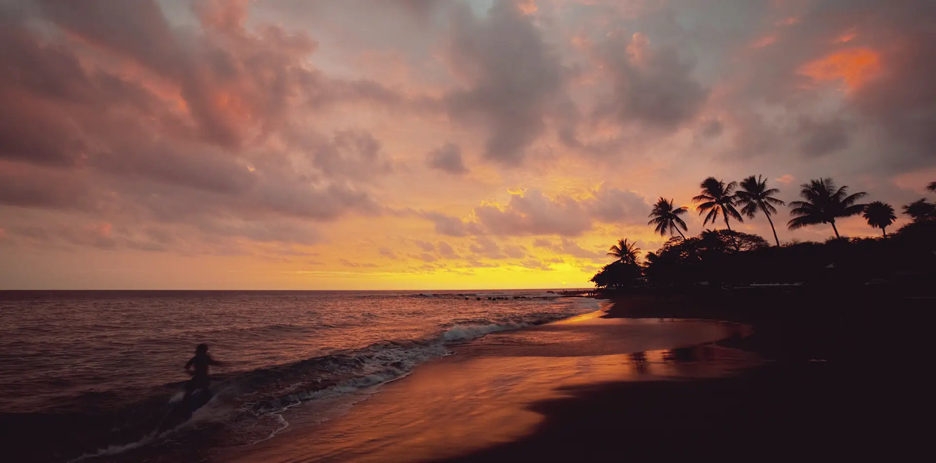 A vivid Kauai beach sunset with silhouettes of people