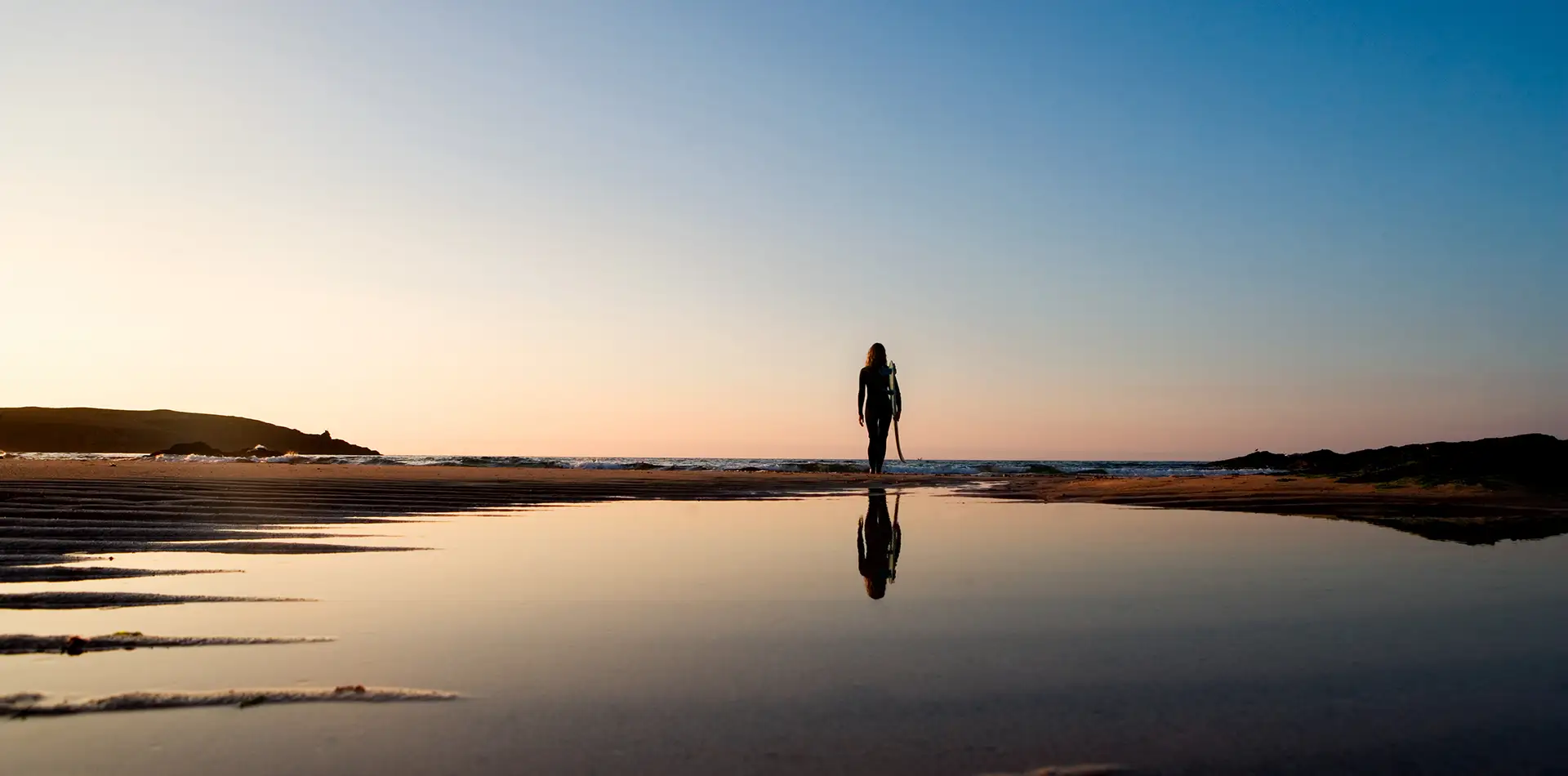 A peaceful, reflective scene such as a person standing by the ocean at sunrise
