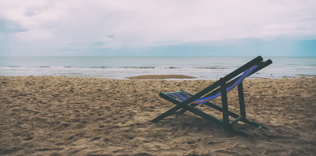 A peaceful scene of an empty beach chair facing the ocean
