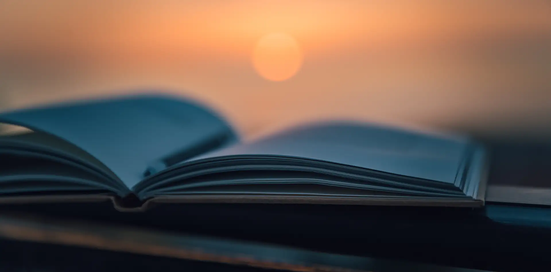 A serene sunrise or sunset scene with an open notebook or book in the foreground