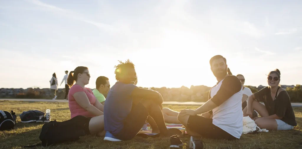 Group of people sitting in a circle outdoors or in a calm space, light flowing between them, symbolizing collective action and consciousness.