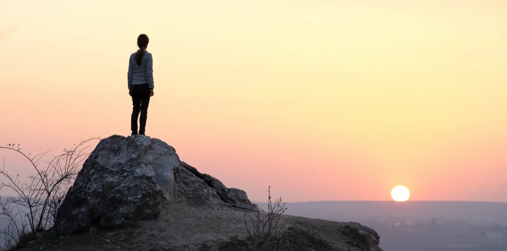 Silhouette of a person standing at sunrise on a cliff or mountain