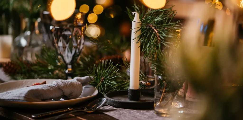 A quiet Christmas Eve scene with a warmly lit table or window at night, soft candlelight, minimal decoration, calm and intimate atmosphere