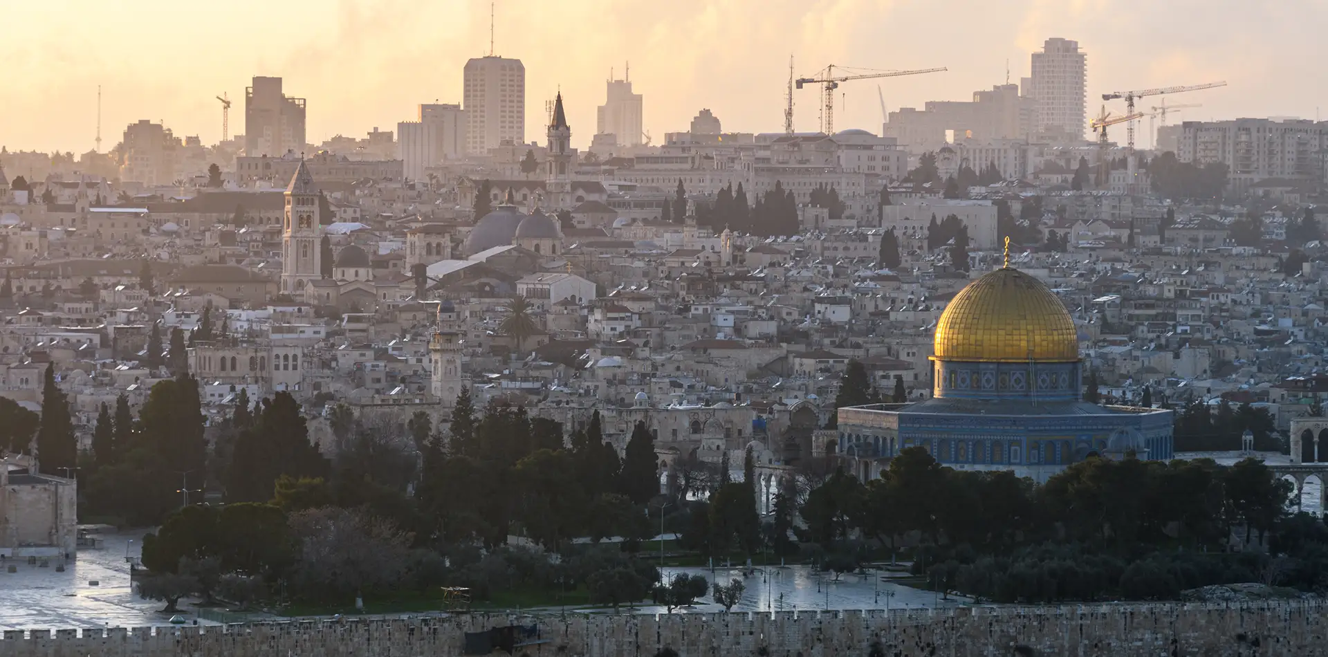 A wide panoramic view of the Middle Eastern landscape, blending ancient historical architecture with a modern city skyline to represent the intersection of religion and technology.