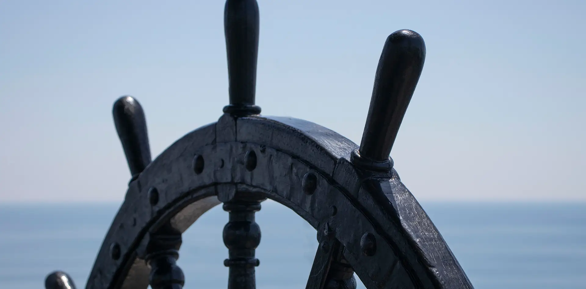 A wooden ship's wheel against a backdrop of a bright guiding star and a cosmic ocean.