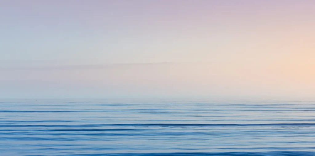 A peaceful ocean shore at dawn, symbolizing the rise and fall of life's tides and the birth of new consciousness.