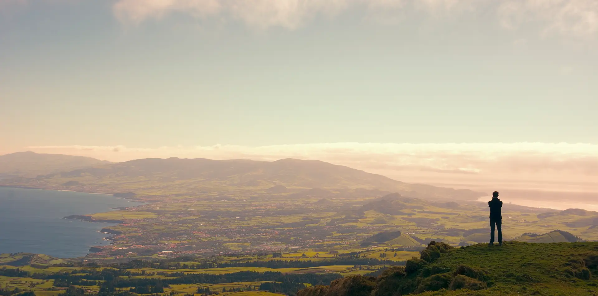 Person standing on a hilltop at sunrise, symbolizing inner peace and reflection amid global change