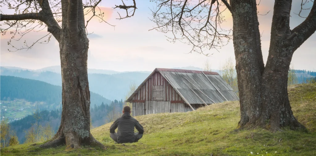 Man meditating in nature at sunrise representing self-awareness and the One Love philosophy