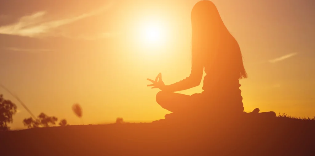Person meditating in warm golden light symbolizing conscious awakening and positive mindset