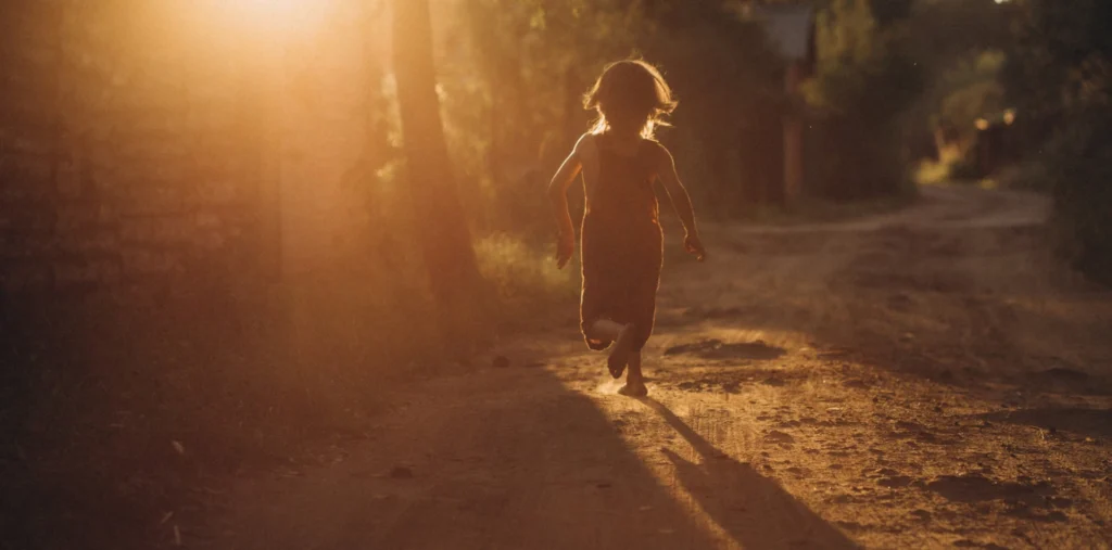 A child's silhouette standing in a golden field of light, symbolizing the inner child and spiritual awakening
