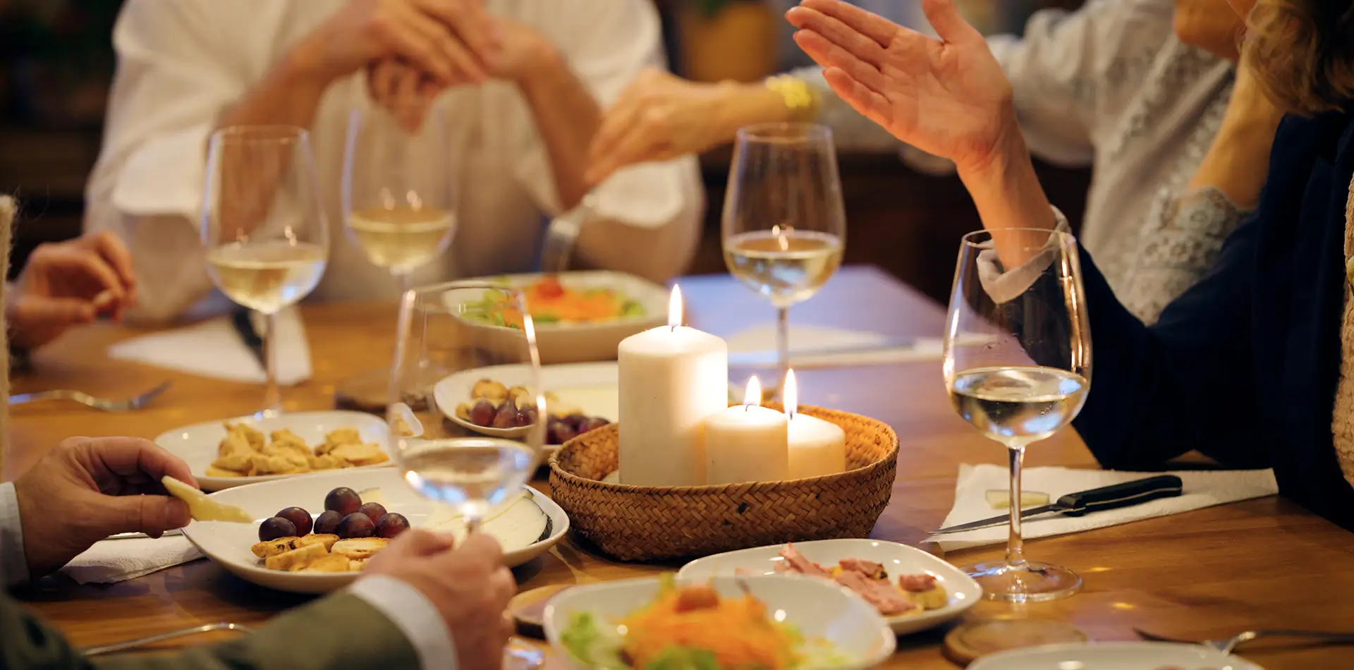 A candlelit dinner table with hands joined in a blessing, evoking a sense of gratitude and spiritual presence