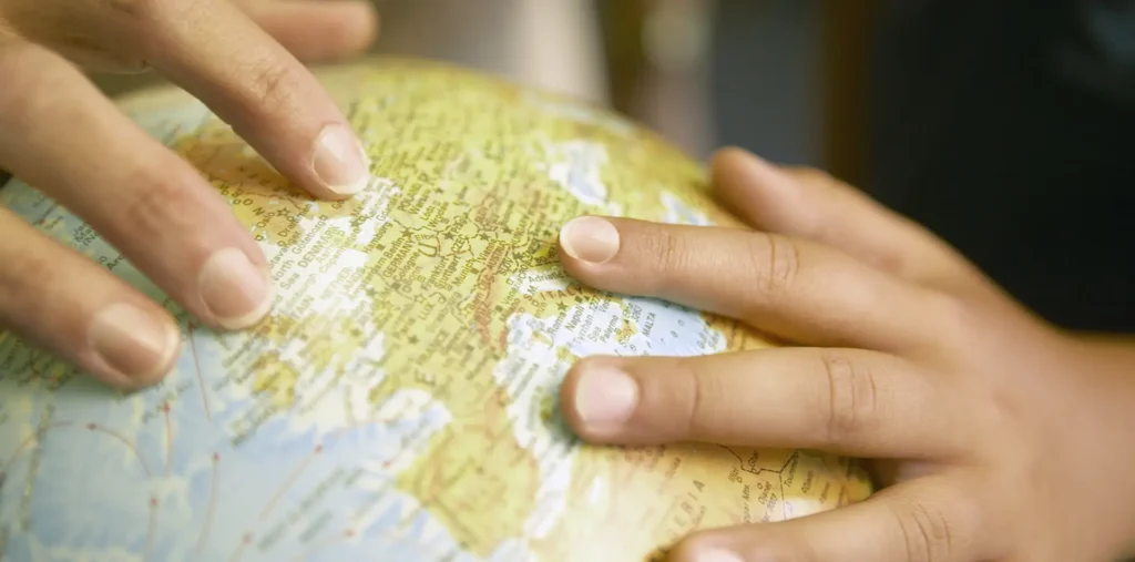 Hands reaching toward a glowing globe symbolising love, peace, and unity across nations