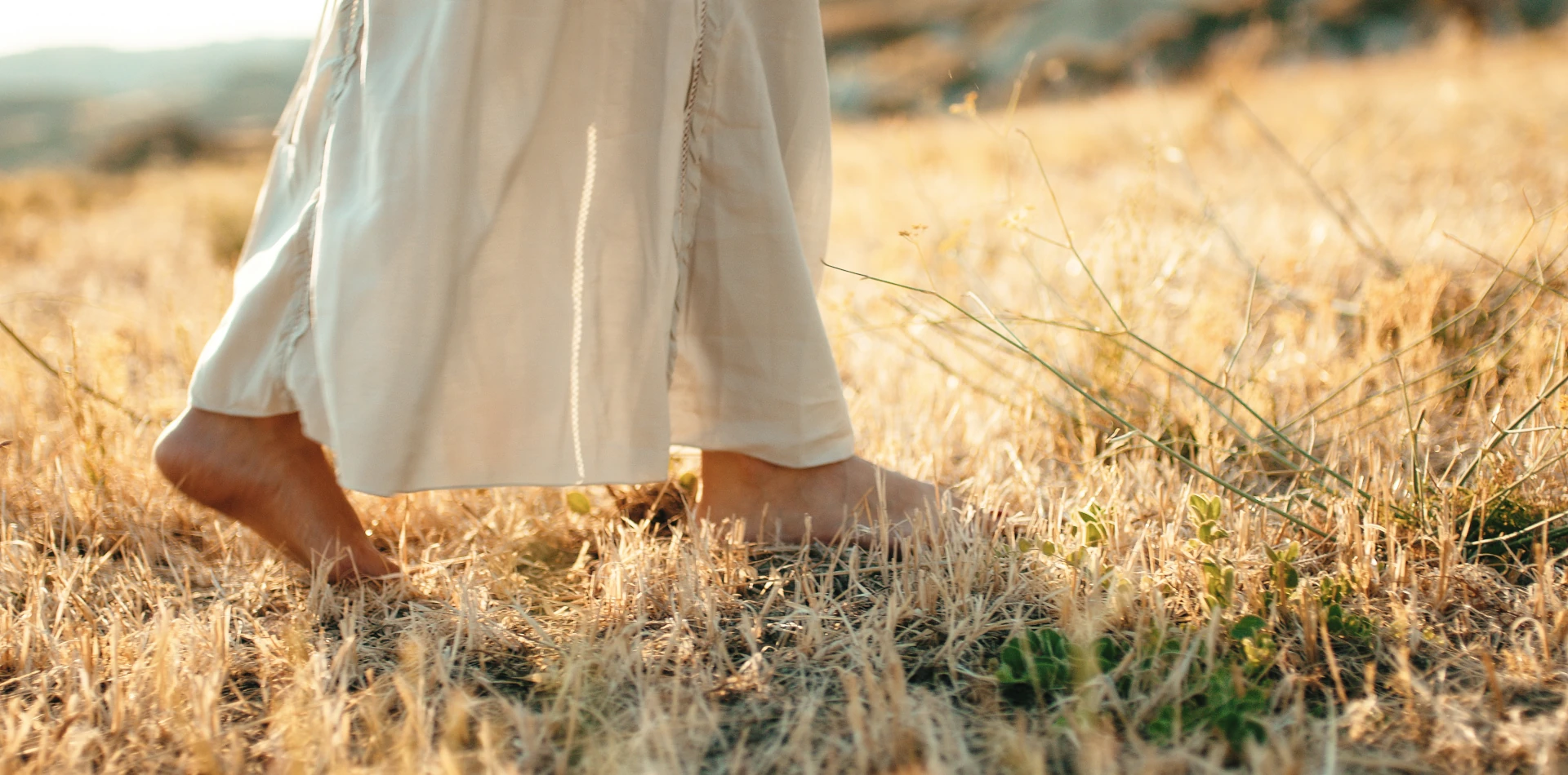 Person standing barefoot on grass at sunrise practicing a morning grounding ritual
