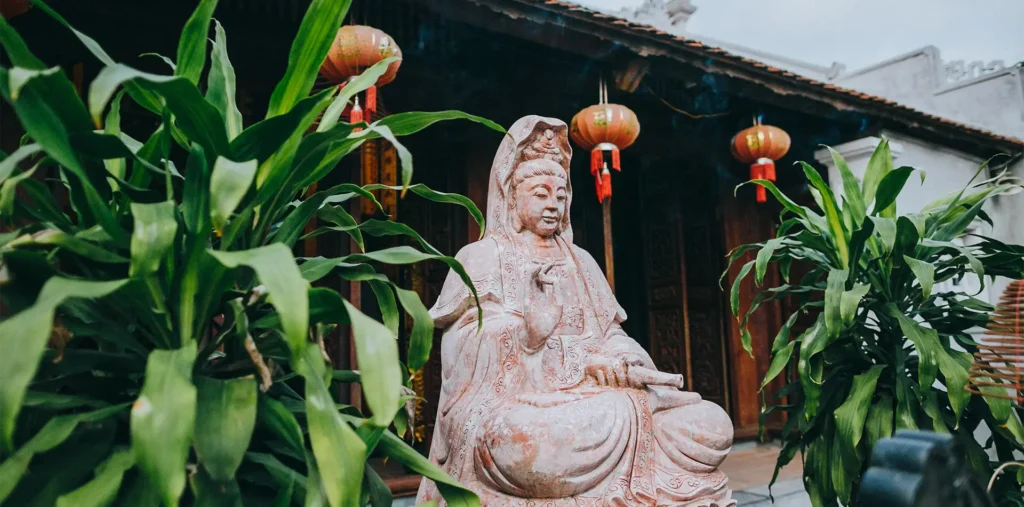 A serene stone statue of Quan Yin surrounded by soft natural light, representing compassion and spiritual reflection