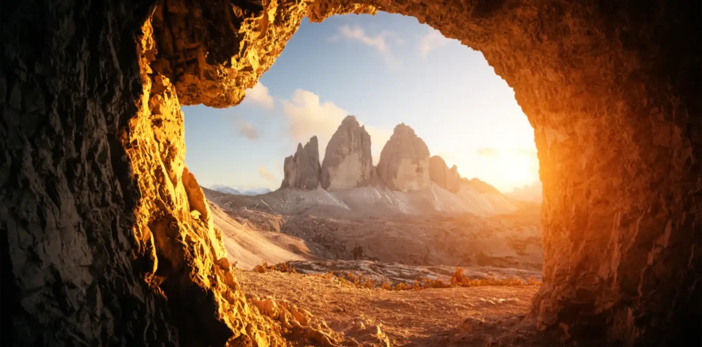Rays of golden light streaming through the entrance of an ancient stone cave, evoking spiritual awakening and the search for hidden truth