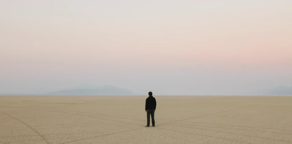 A solitary human figure surrounded by energy and light in an infinite cosmic space