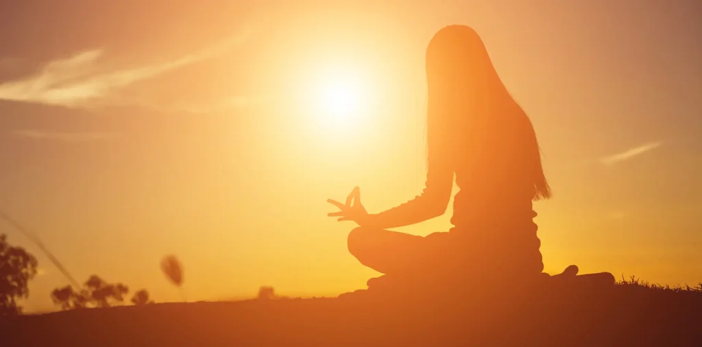 A person in quiet meditation surrounded by warm light, representing the spiritual inward journey of life's second half