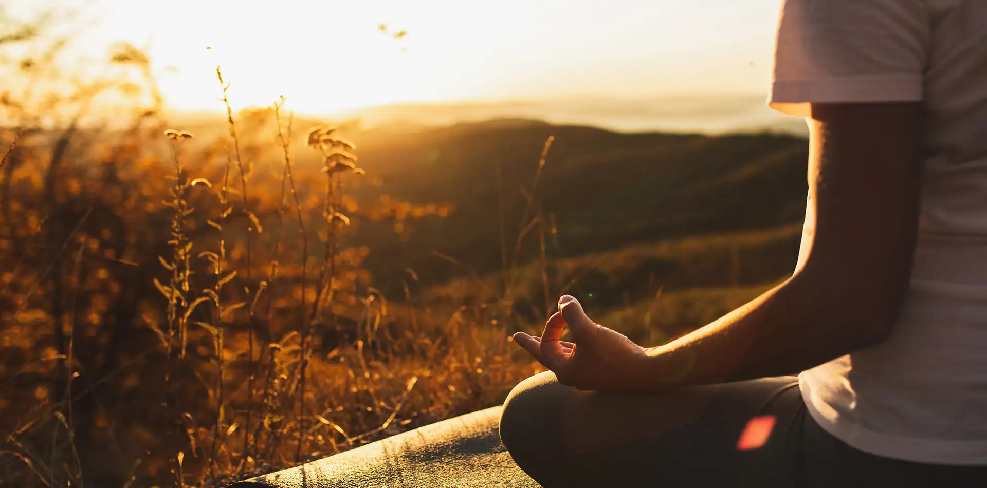An older woman sitting quietly in meditation outdoors at sunrise, reflecting inner calm and how spirituality changes as you age