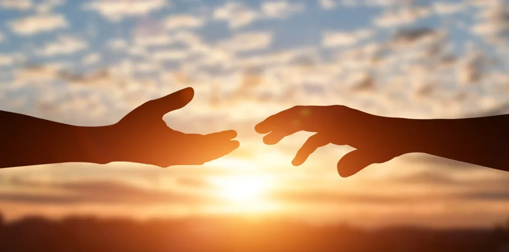 Two open hands reaching toward each other in warm light, expressing the move beyond religious hatred toward unity and peace