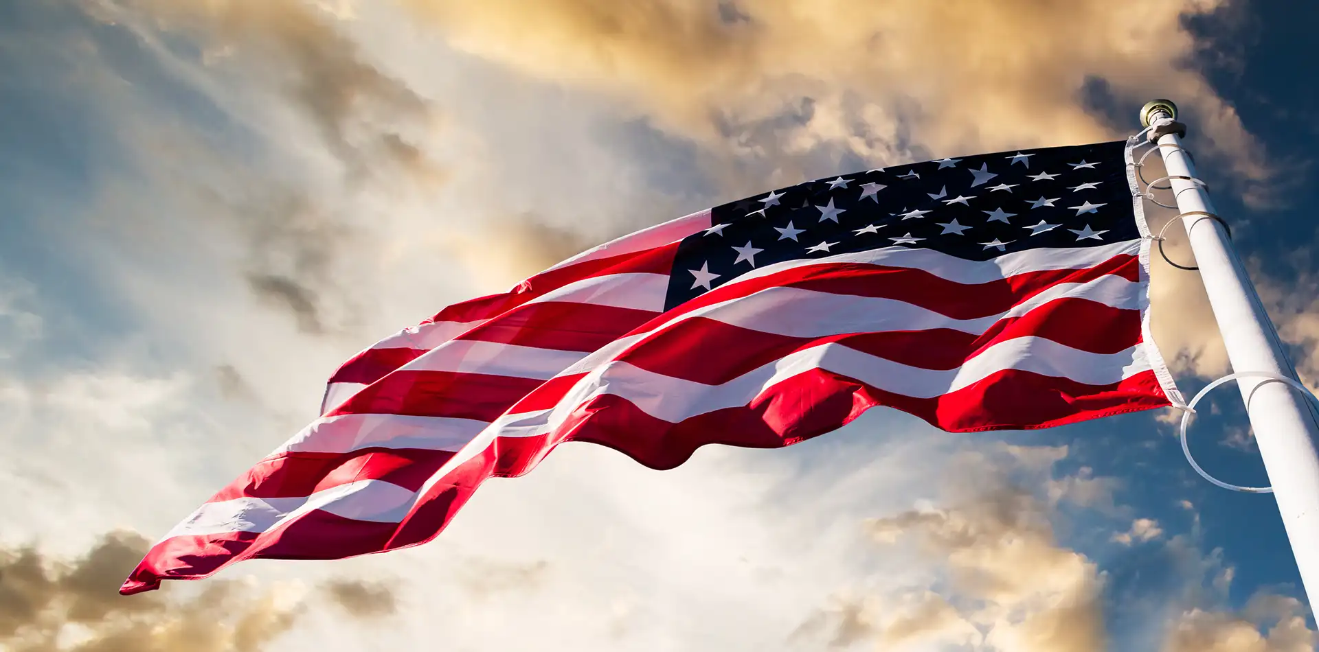 American flag waving at sunset above a peaceful small town street, symbolizing reflection on consciousness and reality