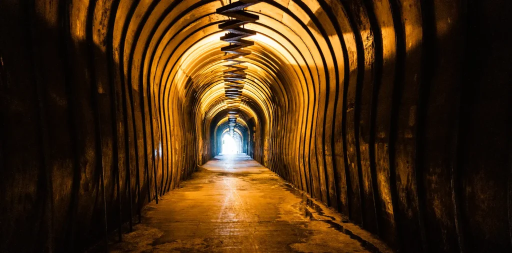 Warm golden light glowing at the end of a dark tunnel surrounded by faint stars