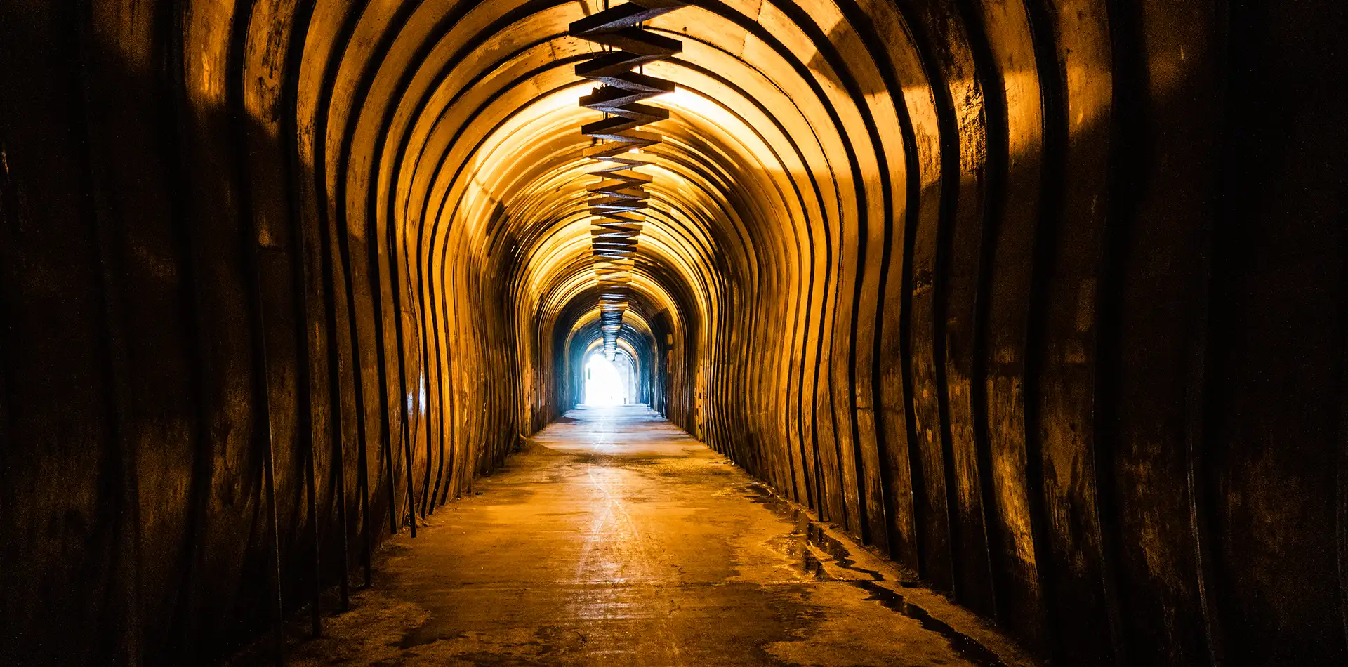 Warm golden light glowing at the end of a dark tunnel surrounded by faint stars