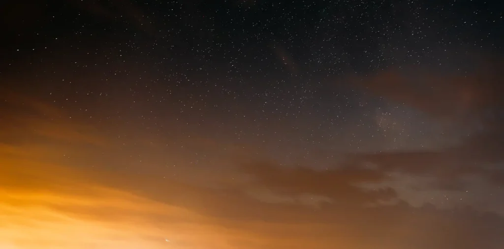 A single bright star radiating golden light above a calm horizon, symbolizing energy and consciousness