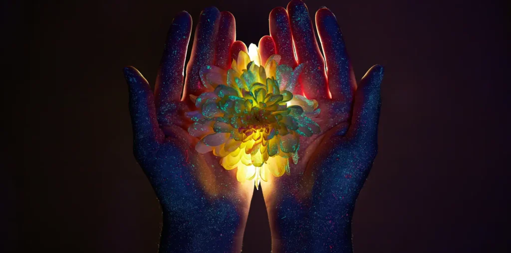 Two hands cupping a soft radiant glow of warm energy against a dark background