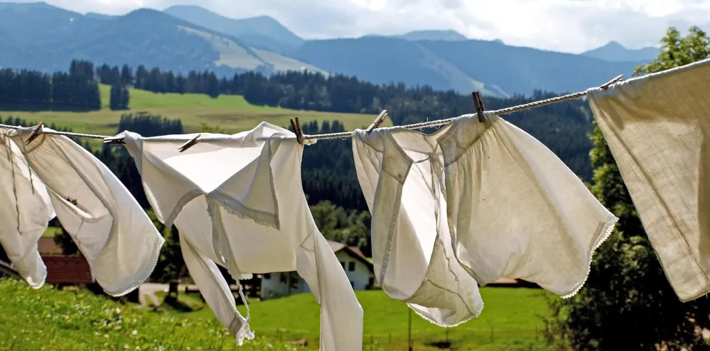 Person wearing flowing natural linen clothing in earthy tones standing outdoors in soft morning light