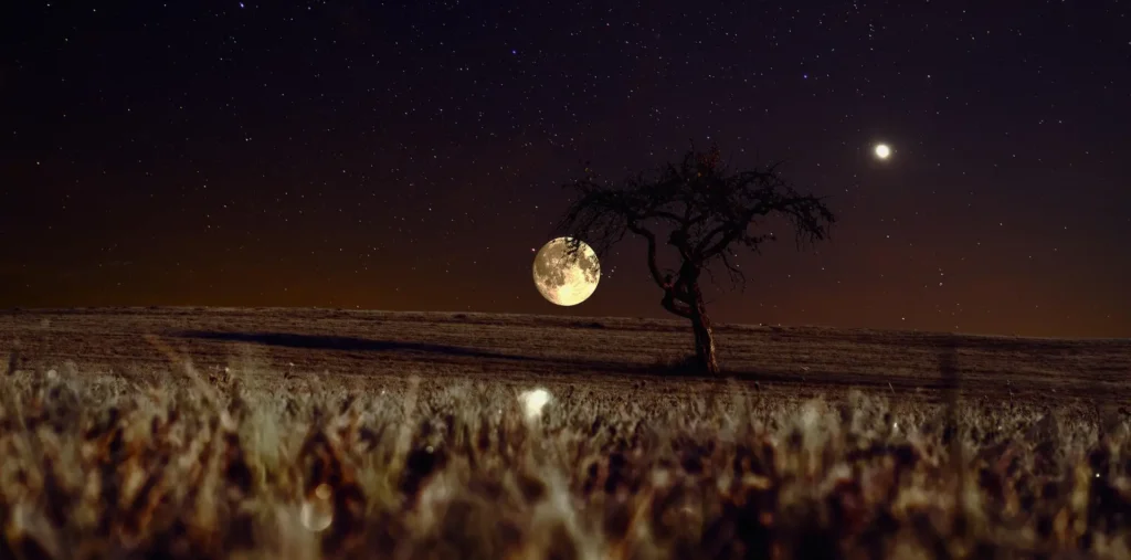 A bright full moon shining over a calm night sky with soft clouds