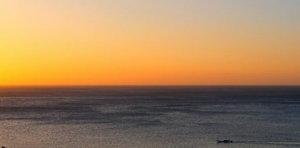 Soft golden sunrise light spreading across a calm ocean horizon at daybreak