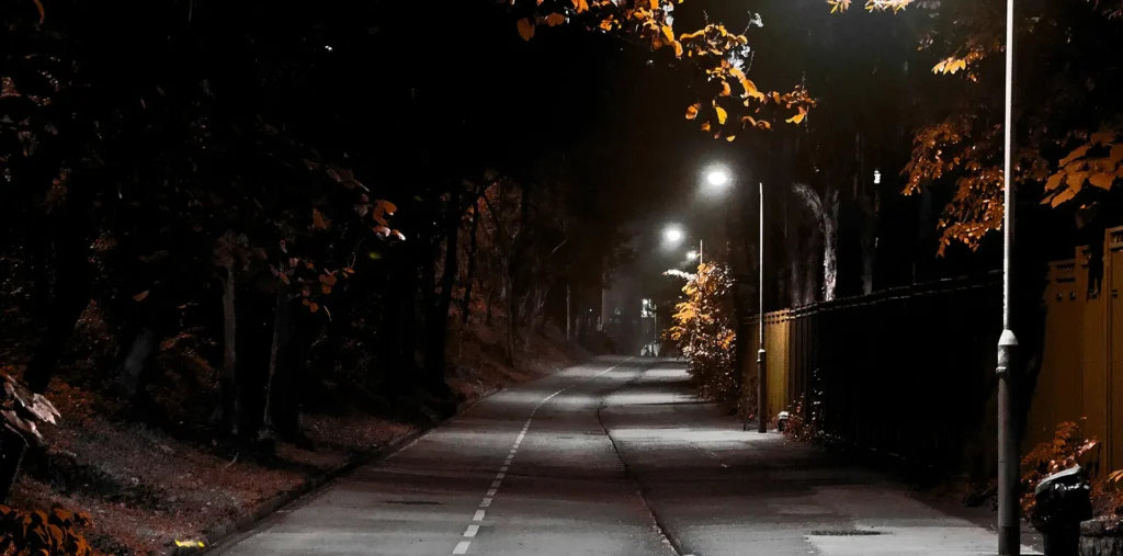 Warm light glowing along a dark road under the night sky symbolizing guidance and safe travels