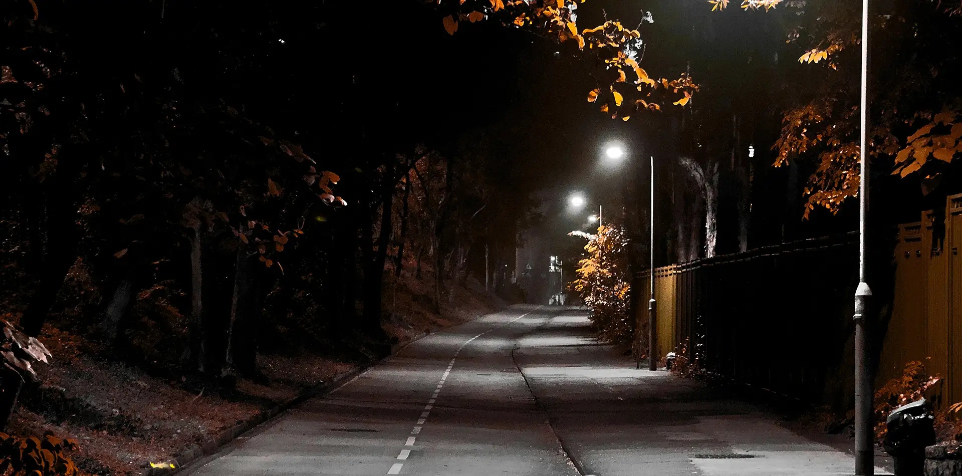 Warm light glowing along a dark road under the night sky symbolizing guidance and safe travels