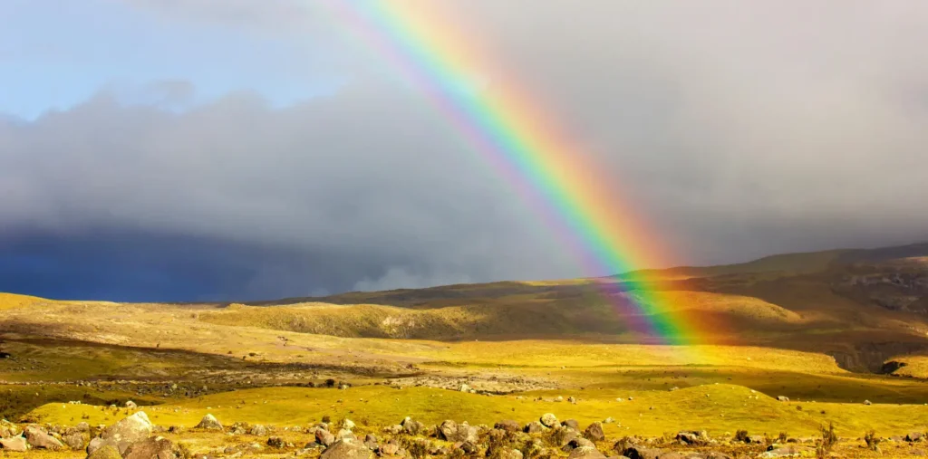 Sunrise casting rainbow-colored rays of light across a calm morning sky over open land