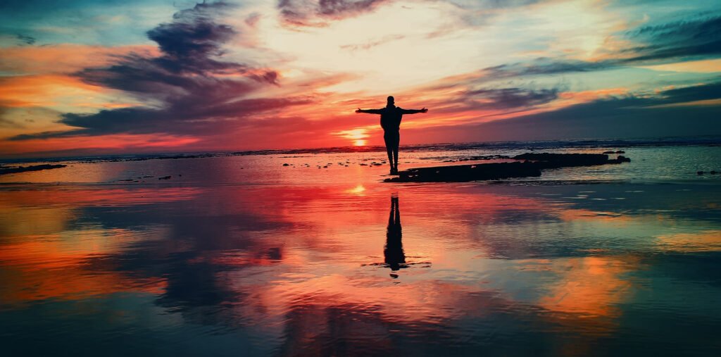 Silhouette of a person meditating at sunset with warm golden light glowing at the center of the body